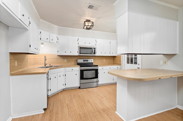 kitchen featuring appliances with stainless steel finishes, a textured ceiling, white cabinetry, and sink