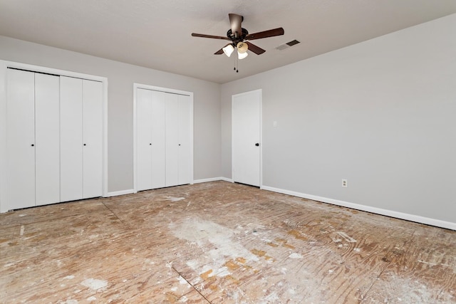 unfurnished bedroom with ceiling fan and multiple closets