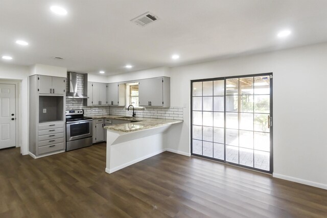 kitchen featuring gray cabinetry, electric stove, wall chimney exhaust hood, decorative backsplash, and kitchen peninsula