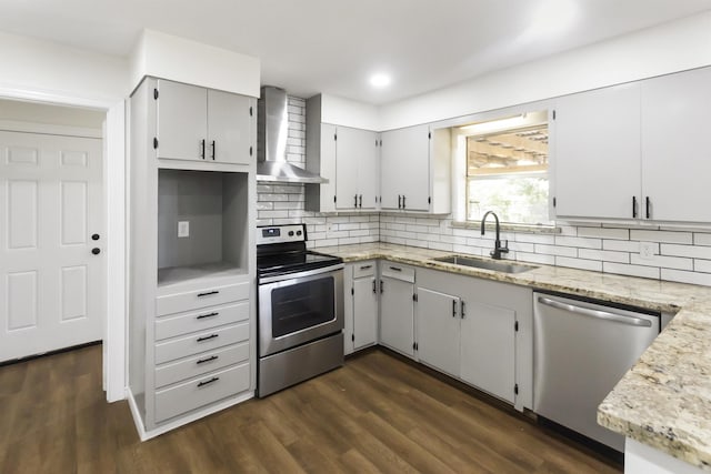 kitchen featuring sink, dark wood-type flooring, wall chimney range hood, tasteful backsplash, and appliances with stainless steel finishes