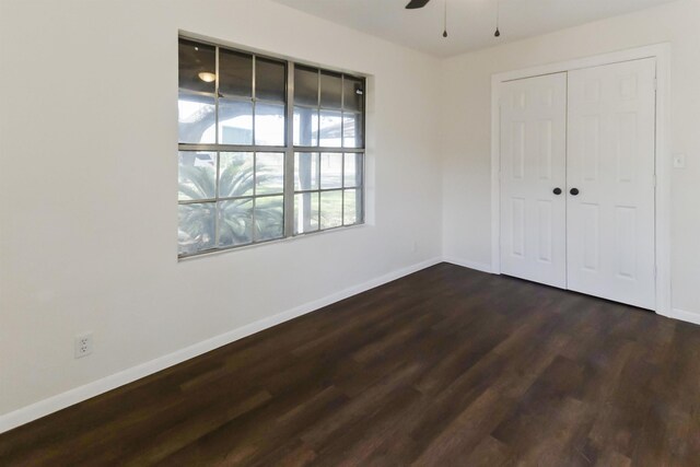 unfurnished bedroom featuring ceiling fan, dark hardwood / wood-style floors, and a closet