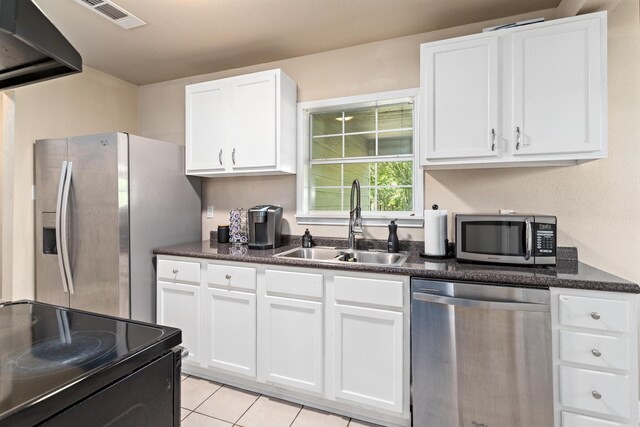 10775 Old Voth Rd, Beaumont, TX 77713 - kitchen featuring appliances with stainless steel finishes, a sink, dark countertops, white cabinetry, and light tile patterned floors