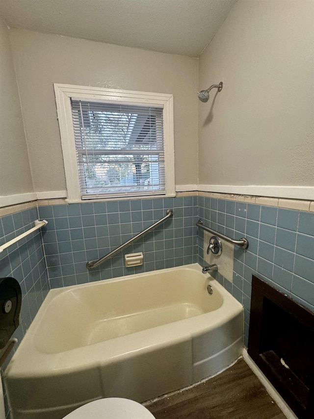 bathroom featuring hardwood / wood-style flooring, toilet, a bath, and tile walls