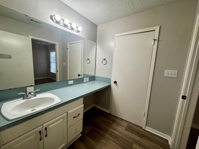 bathroom with vanity, wood-type flooring, and a textured ceiling