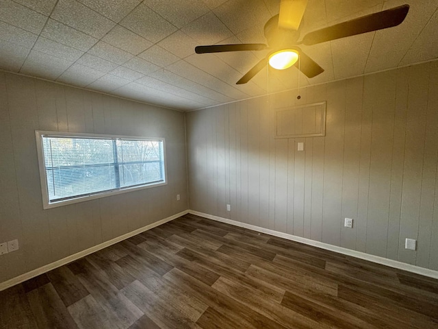 unfurnished room featuring dark hardwood / wood-style flooring, wooden walls, and ceiling fan