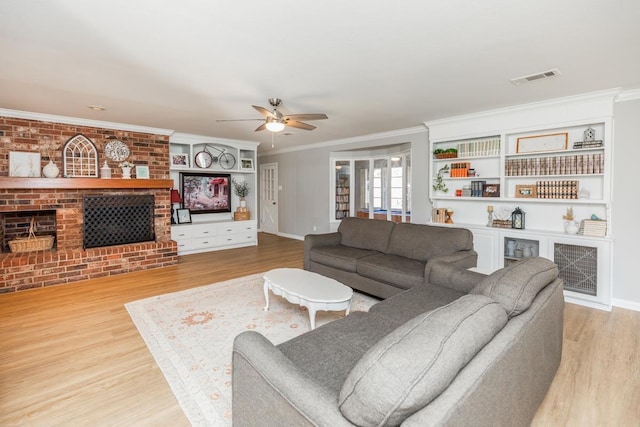 living room featuring a fireplace, light hardwood / wood-style floors, ceiling fan, and crown molding