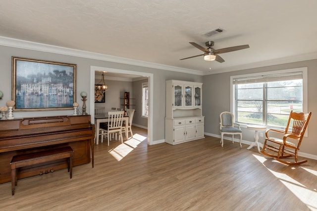 living area featuring ceiling fan with notable chandelier, light hardwood / wood-style flooring, and ornamental molding