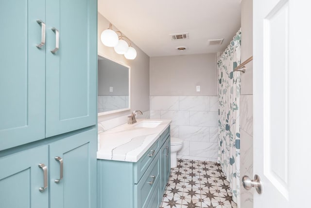 bathroom with a shower with curtain, vanity, toilet, and tile walls