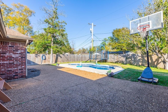 view of pool with a lawn, a trampoline, and a patio