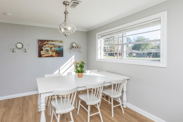 dining room featuring a chandelier, ornamental molding, and light hardwood / wood-style flooring