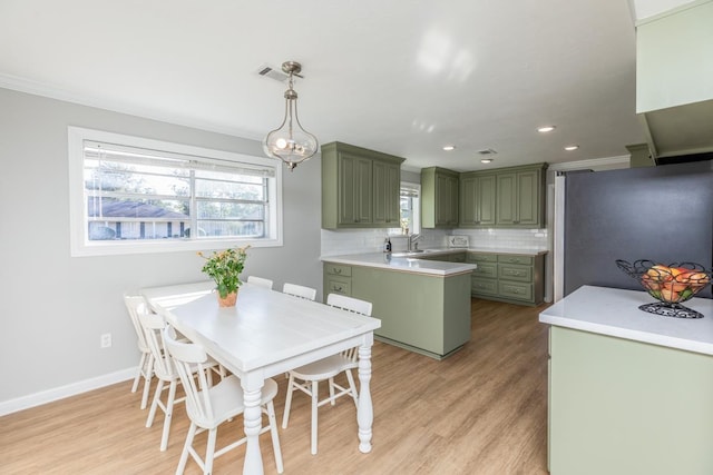 kitchen featuring pendant lighting, sink, green cabinetry, stainless steel fridge, and tasteful backsplash