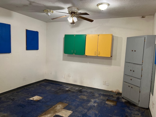 unfurnished room with a textured ceiling, dark floors, ceiling fan, and baseboards