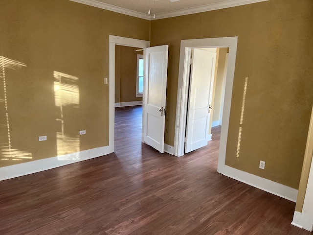 spare room with baseboards, ornamental molding, and dark wood-style flooring