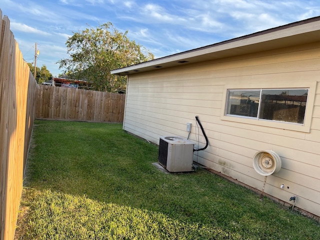 view of side of home with cooling unit, a fenced backyard, and a lawn