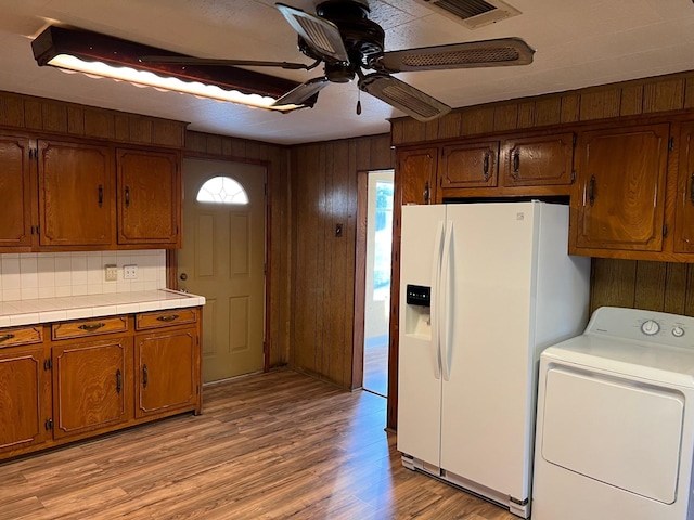 kitchen featuring tile countertops, white refrigerator with ice dispenser, visible vents, light wood-type flooring, and washer / clothes dryer