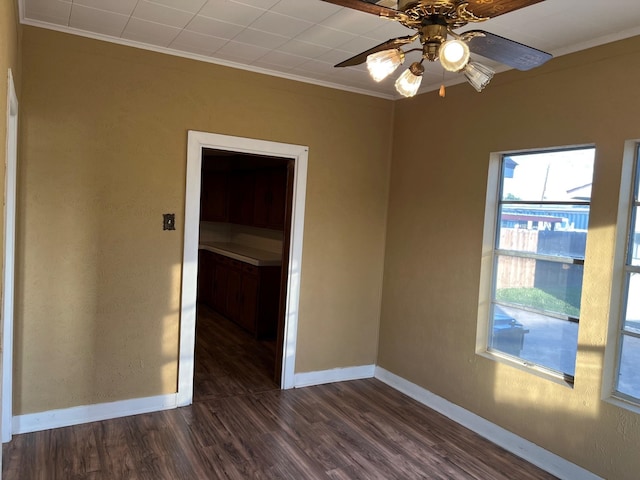 unfurnished room featuring ornamental molding, dark wood-style flooring, a ceiling fan, and baseboards