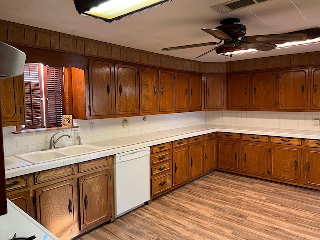 kitchen with visible vents, decorative backsplash, white dishwasher, a sink, and light wood-type flooring