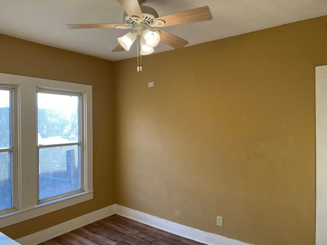 spare room featuring dark wood-type flooring, baseboards, and a ceiling fan