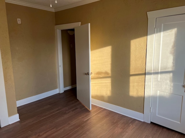 spare room with ornamental molding, wood finished floors, and baseboards