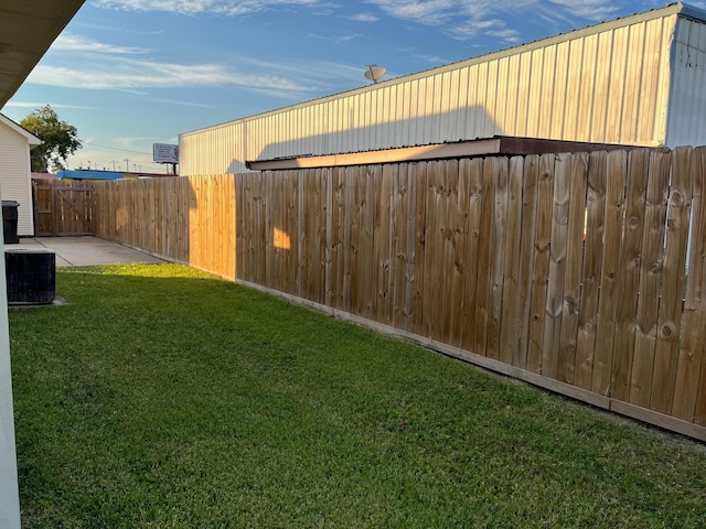 view of yard with a patio area, fence, and central AC unit