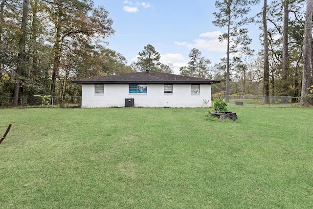 rear view of house featuring central air condition unit and a lawn