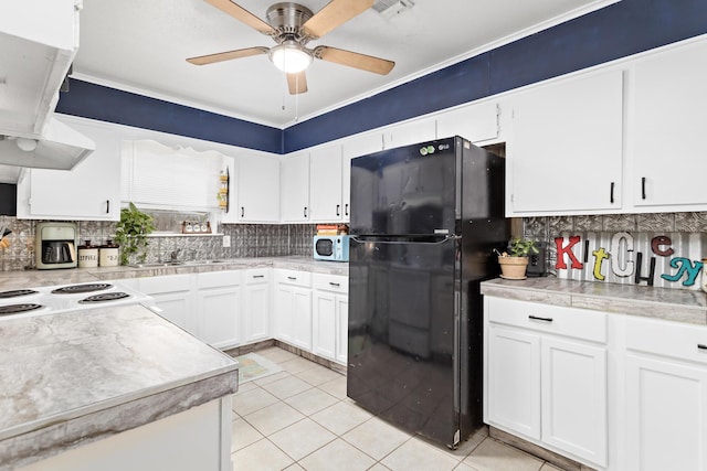 kitchen featuring range hood, white cabinetry, black fridge, and light tile patterned flooring