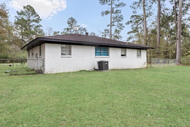 back of house featuring central AC unit and a lawn