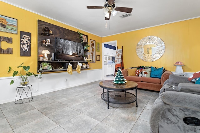 tiled living room with ceiling fan and ornamental molding