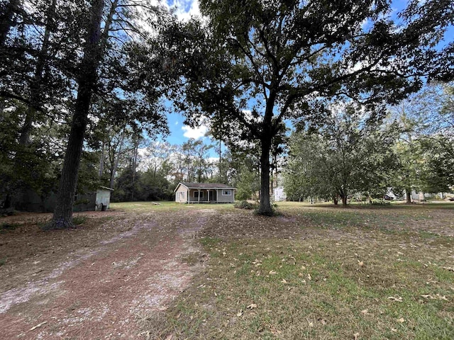 138 Ned Rd, Lumberton, TX 77657 - view of front facade featuring dirt driveway, an outbuilding, and view of wooded area