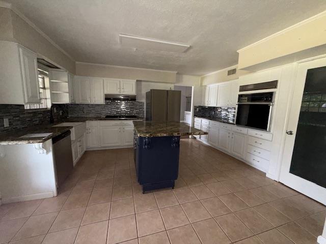 176 Ridgewood St, Bridge City, TX 77611 - kitchen featuring freestanding refrigerator, black oven, stainless steel dishwasher, white cabinets, and a textured ceiling