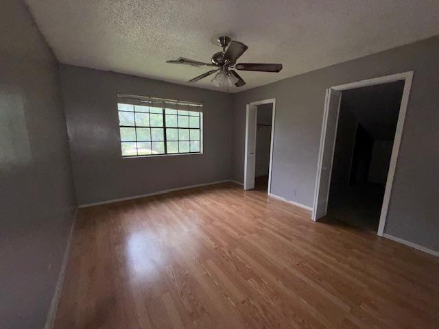 176 Ridgewood St, Bridge City, TX 77611 - unfurnished bedroom featuring wood finished floors, a textured ceiling, and a ceiling fan