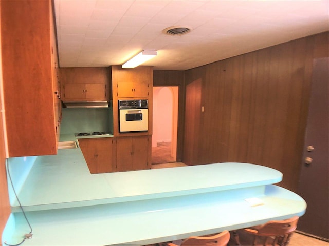 3812 30th, Port Arthur, TX 77642 - kitchen with white oven, wood walls, cooktop, and a peninsula