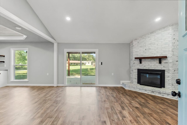 unfurnished living room with a fireplace, hardwood / wood-style flooring, and lofted ceiling