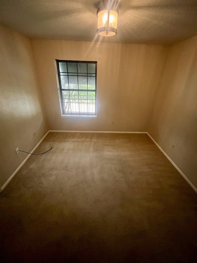 carpeted empty room featuring a textured ceiling and baseboards