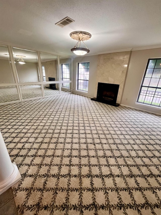 unfurnished living room with carpet floors, ornamental molding, a textured ceiling, and a premium fireplace