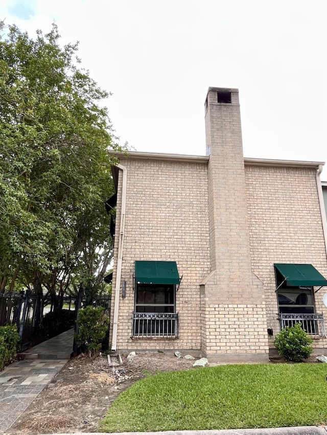 view of front of property featuring a chimney and brick siding