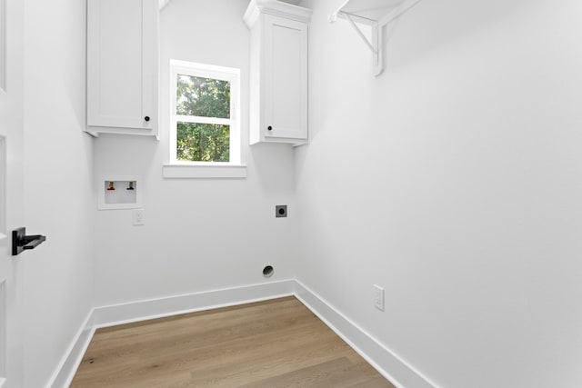 clothes washing area featuring electric dryer hookup, cabinets, washer hookup, and light hardwood / wood-style floors