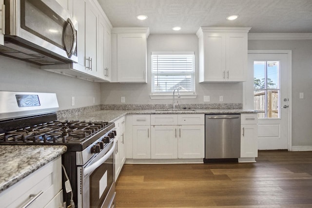 kitchen with a sink, stainless steel appliances, white cabinets, and dark wood finished floors