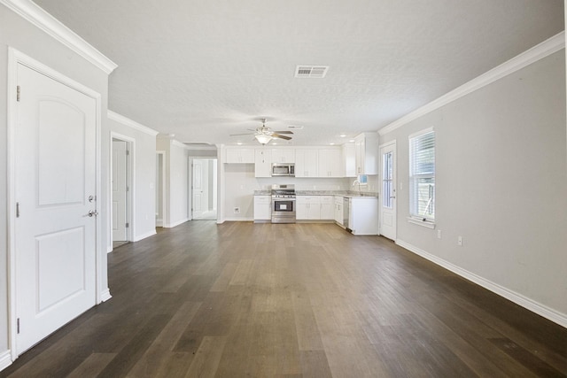 unfurnished living room featuring baseboards, visible vents, dark wood finished floors, a sink, and crown molding