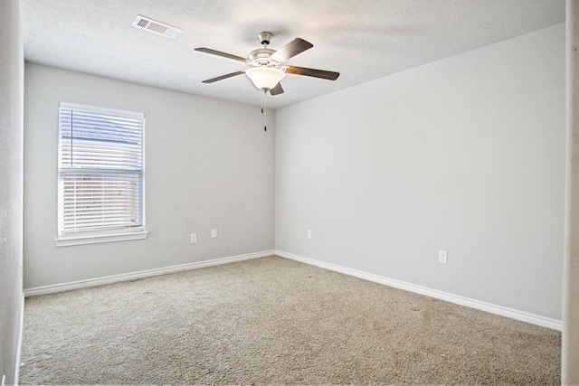 spare room featuring visible vents, a textured ceiling, carpet flooring, baseboards, and ceiling fan