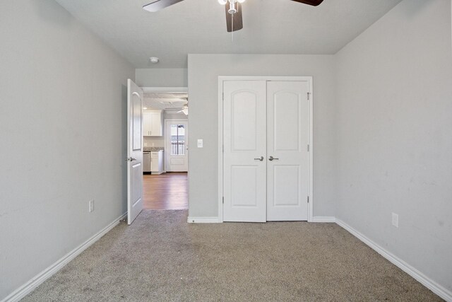 unfurnished bedroom featuring a closet, carpet floors, baseboards, and a ceiling fan