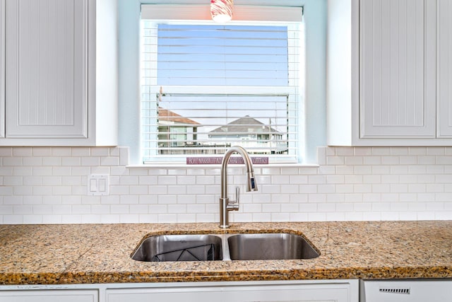 kitchen with white cabinets, decorative backsplash, light stone counters, and sink