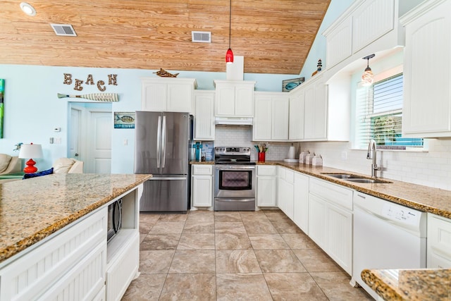 kitchen featuring lofted ceiling, sink, hanging light fixtures, light stone counters, and stainless steel appliances