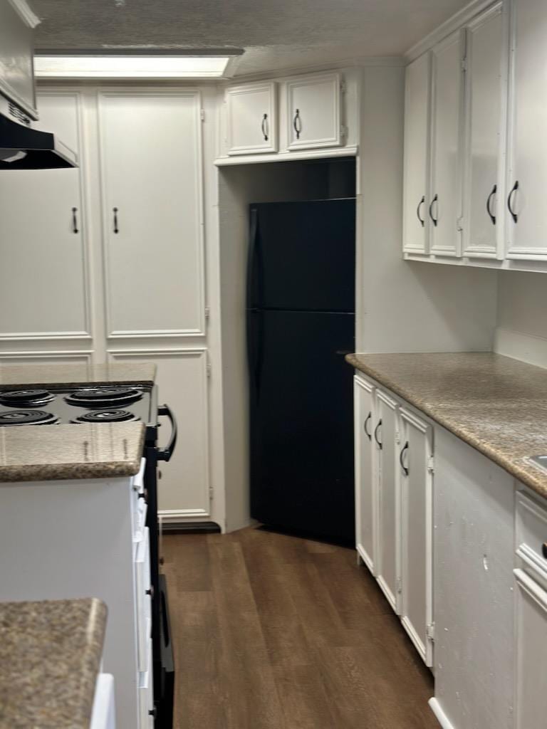 kitchen featuring freestanding refrigerator, white cabinetry, range with electric stovetop, under cabinet range hood, and dark wood-type flooring