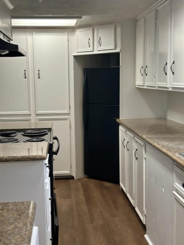 kitchen featuring freestanding refrigerator, white cabinetry, range with electric stovetop, under cabinet range hood, and dark wood-type flooring
