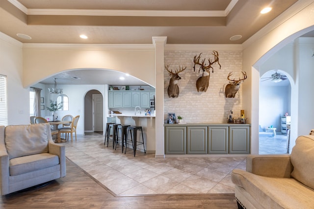 735 Jacob Cir, Orange, TX 77630 - living area featuring arched walkways, ceiling fan, a tray ceiling, a chandelier, and light wood-style floors