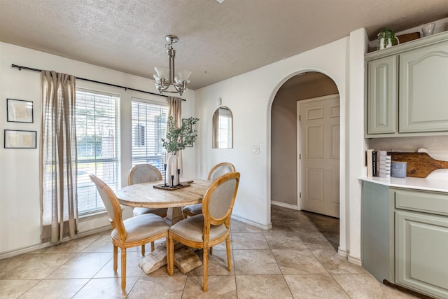 735 Jacob Cir, Orange, TX 77630 - dining space featuring a chandelier, arched walkways, a textured ceiling, light tile patterned floors, and baseboards