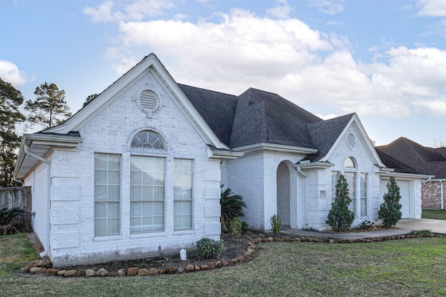 735 Jacob Cir, Orange, TX 77630 - view of front facade with an attached garage, a shingled roof, a front yard, and brick siding