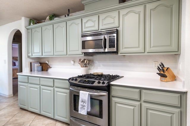 735 Jacob Cir, Orange, TX 77630 - kitchen featuring appliances with stainless steel finishes, arched walkways, light tile patterned floors, and light countertops