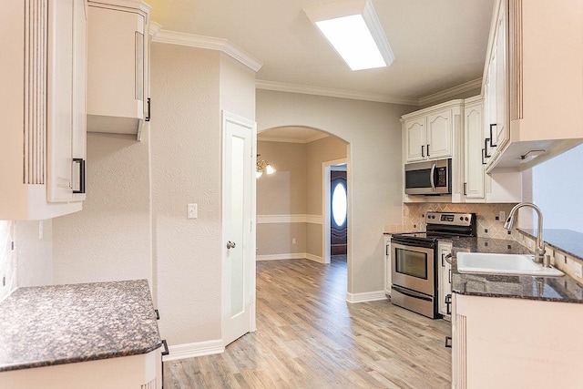 kitchen featuring sink, ornamental molding, light hardwood / wood-style floors, white cabinetry, and stainless steel appliances